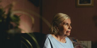 Una mujer mayor sentada sola en su casa.