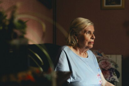 Una mujer mayor sentada sola en su casa.