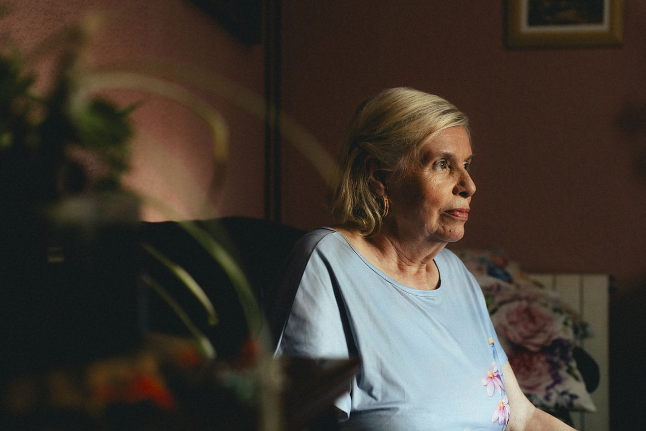 Una mujer mayor sentada sola en su casa.